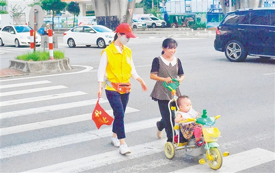 江海区一名志愿者引导市民安全过马路。 江海区一名志愿者引导市民安全过马路。